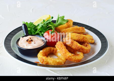 Calamari rings fried with spicy sauce and rucola. Mediterranean lifestyle. Healthy food. Stock Photo