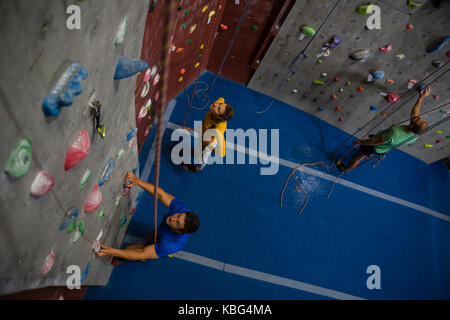 High angle view of athletes examining climbing wall in health club Stock Photo