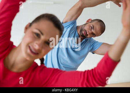 Portrait of male instructor exercising with female student in health club Stock Photo