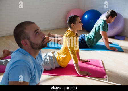 Yoga instructor with students practicing cobra pose in health club Stock Photo