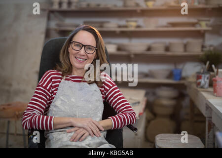 Female potter relaxing on chair in pottery shop Stock Photo