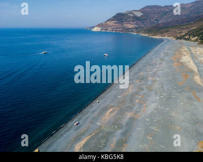 Aerial view of the black pebble beach, Nonza, Geometric designs made with stones, sailboats and moored boats near the beach.Cap Corse, Corsica, France Stock Photo