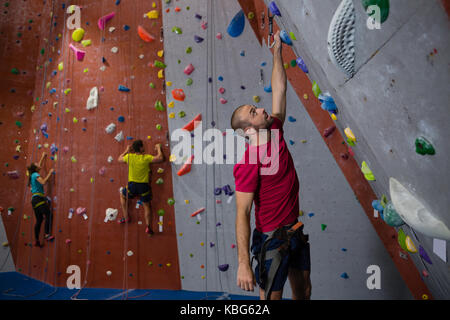 Dedicated athletes and trainer climbing wall in fitness club Stock Photo