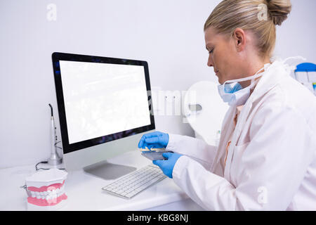 Side view of dentist working while sitting by computer at clinic Stock Photo