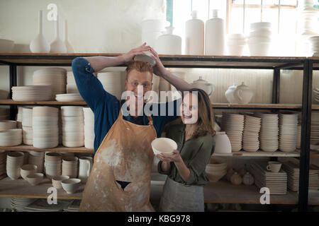 Portrait of male and female potter holding bowl in pottery workshop Stock Photo