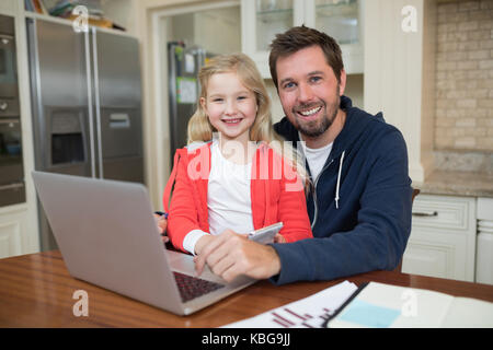 Portrait of father and daughter working on laptop Stock Photo