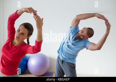 Female student with male instructor exercising in yoga studio Stock Photo