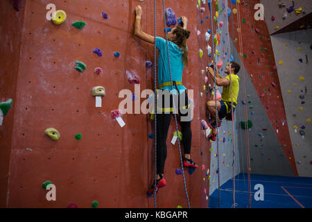 Dedicated athletes climbing wall in heath club Stock Photo