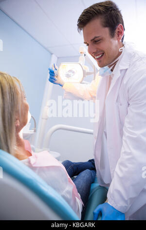 Low angle view of dentist adjusting lamp while looking at patient in clinic Stock Photo