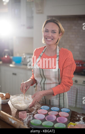 Portrait of smiling woman mixing eggs and wheat flour in a bowl Stock Photo
