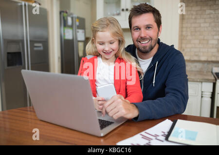 Father and daughter working on laptop at home Stock Photo