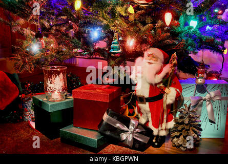 Night scene with shining Christmas tree close up, Santa Clause and gift boxes under it. Good for a seasonal greeting cards. Stock Photo