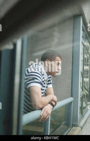 Thoughtful man standing near window Stock Photo