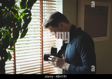 Man holding vintage camera near window at home Stock Photo