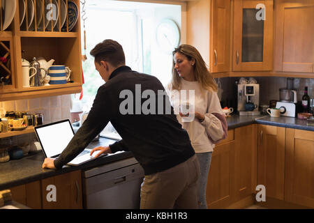 Couple using laptop in kitchen at home Stock Photo