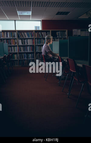 Man studying at desk in library Stock Photo