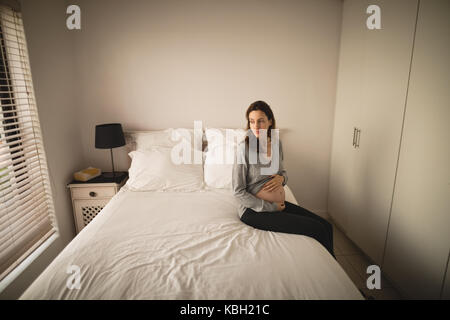 Pregnant woman sitting on the bed at home Stock Photo