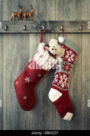 Pair of Christmas stockings hanging from hooks with reindeer figures sitting on the ledge Stock Photo