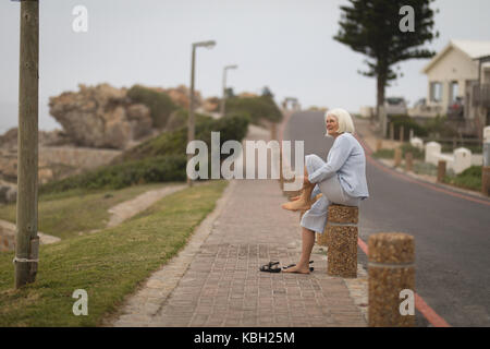 Thoughtful senior woman sitting on bollard Stock Photo