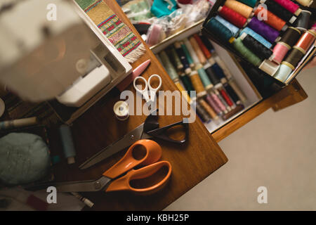 Sewing machine, scissors and threads on table at home Stock Photo
