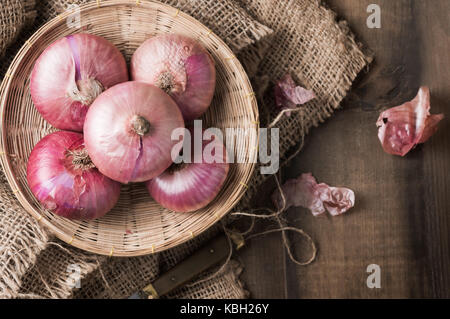 red onions in bamboo basket and on wood background, vegetable for cooking food Stock Photo
