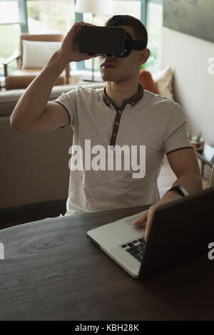 Man using virtual reality headset while working on laptop art home Stock Photo