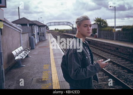 Man using mobile phone at railway platform Stock Photo