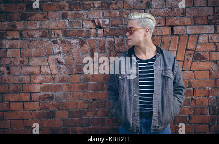 Stylish man posing against brick wall Stock Photo