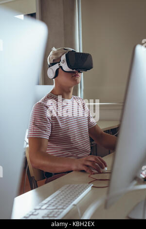 Man using virtual reality while working on personal computer in office Stock Photo