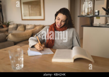 Pregnant woman writing in a book while sitting Stock Photo
