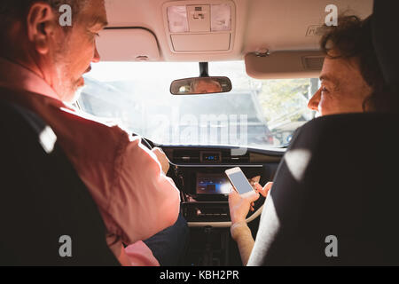 Couple using mobile phone while travelling in car Stock Photo