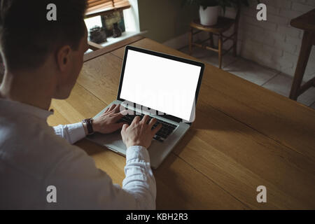 Man at desk using laptop desk in home Stock Photo
