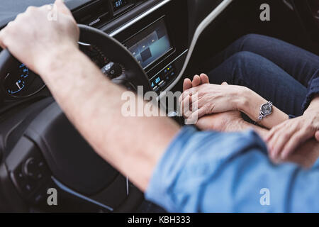 Mid-section of couple holding hands in the car Stock Photo