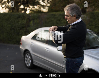 Senior man checking time on his watch on the road Stock Photo