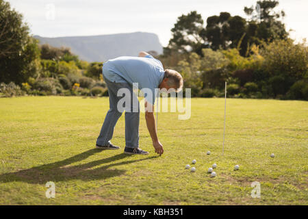 Senior man placing golf ball in golf course Stock Photo