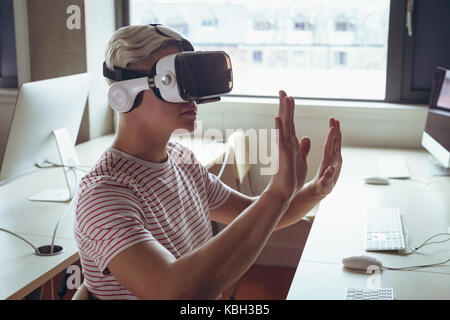 Man using virtual reality headset in office Stock Photo