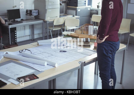 Mid section of architect standing with hands on hip at table in studio Stock Photo
