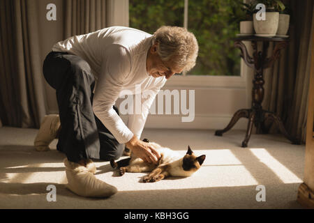 Senior man playing with his cat at home Stock Photo