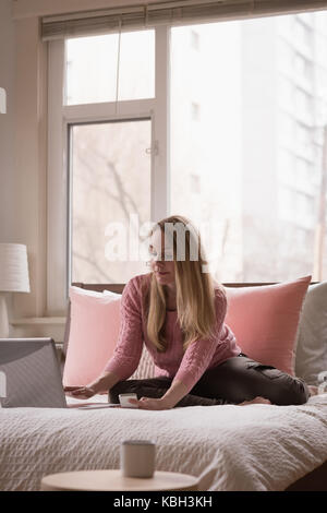 Young woman using laptop on bed at home Stock Photo