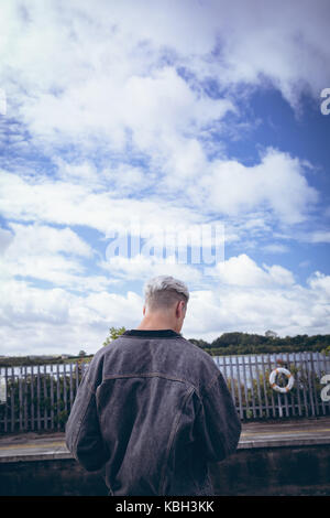 Rear view of man standing on platform at railway station Stock Photo