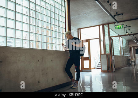 University male student using mobile phone in the corridor of college Stock Photo