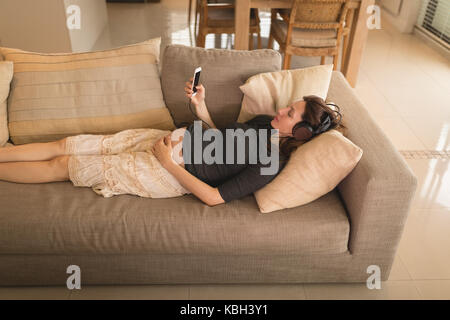 Pregnant woman listening to music at home Stock Photo