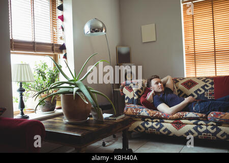 Man relaxing on sofa in living room at home Stock Photo