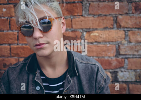 Confident man wearing sunglasses against brick wall Stock Photo