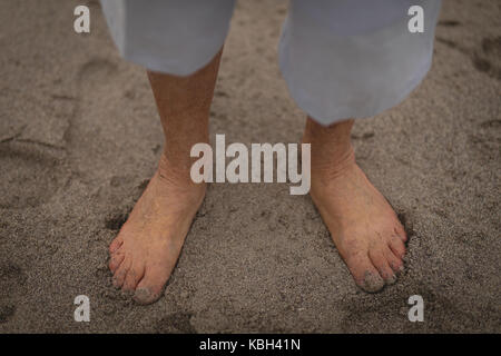 Senior woman standing on sand at beach Stock Photo