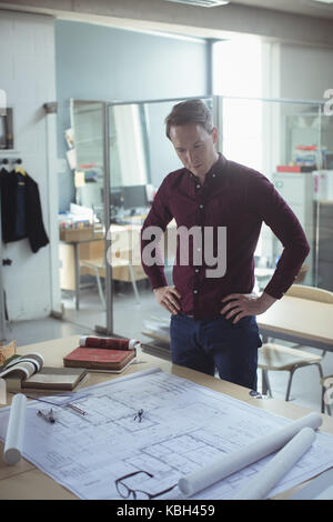 Thoughtful architect looking at blueprint in studio Stock Photo