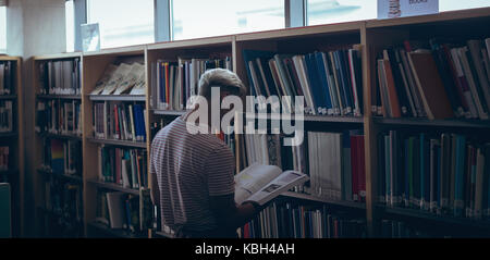 Attentive man reading book in library Stock Photo