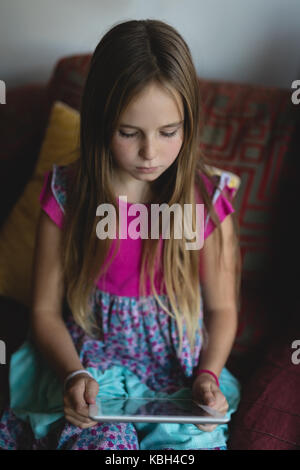 Girl using digital tablet on sofa in living room at home Stock Photo
