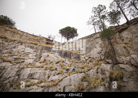 Low angle view of friends climbing a mountain Stock Photo