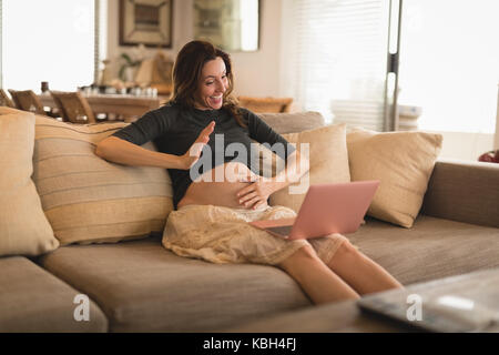 Pregnant woman video calling on laptop at home Stock Photo
